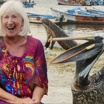 Smiling traveller in a sun hat standing by a harbour of fishing boats